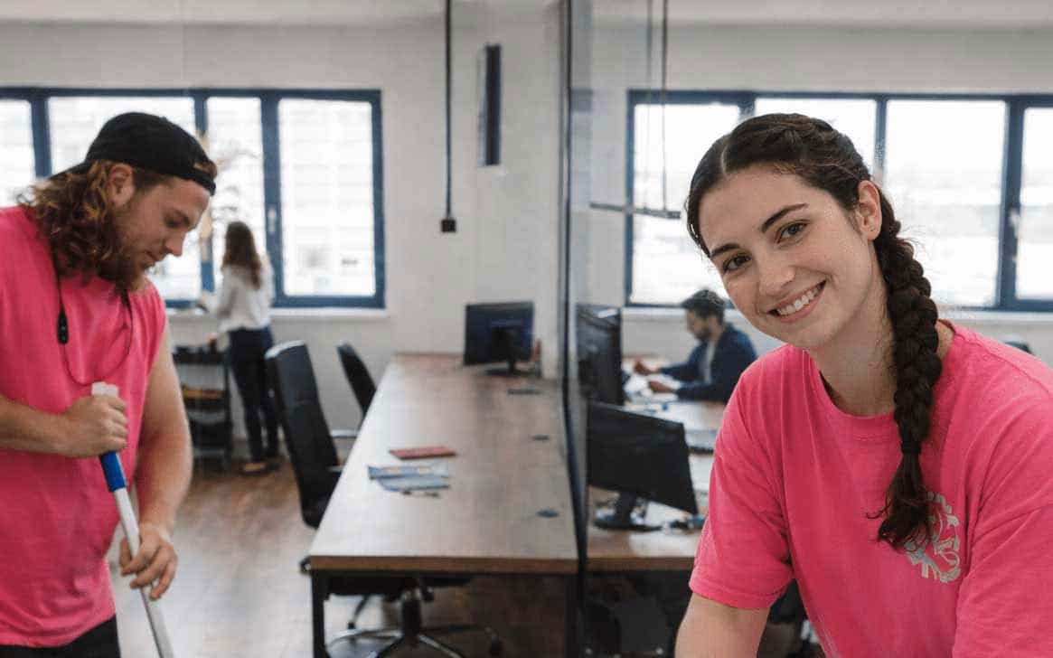 Reinigungsteam in einem hellen Büro mit mehreren Arbeitsplätzen
