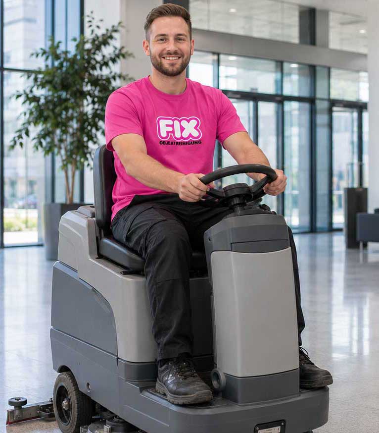 Reinigungskraft im pinken FIX-Shirt auf einer Bodenreinigungsmaschine