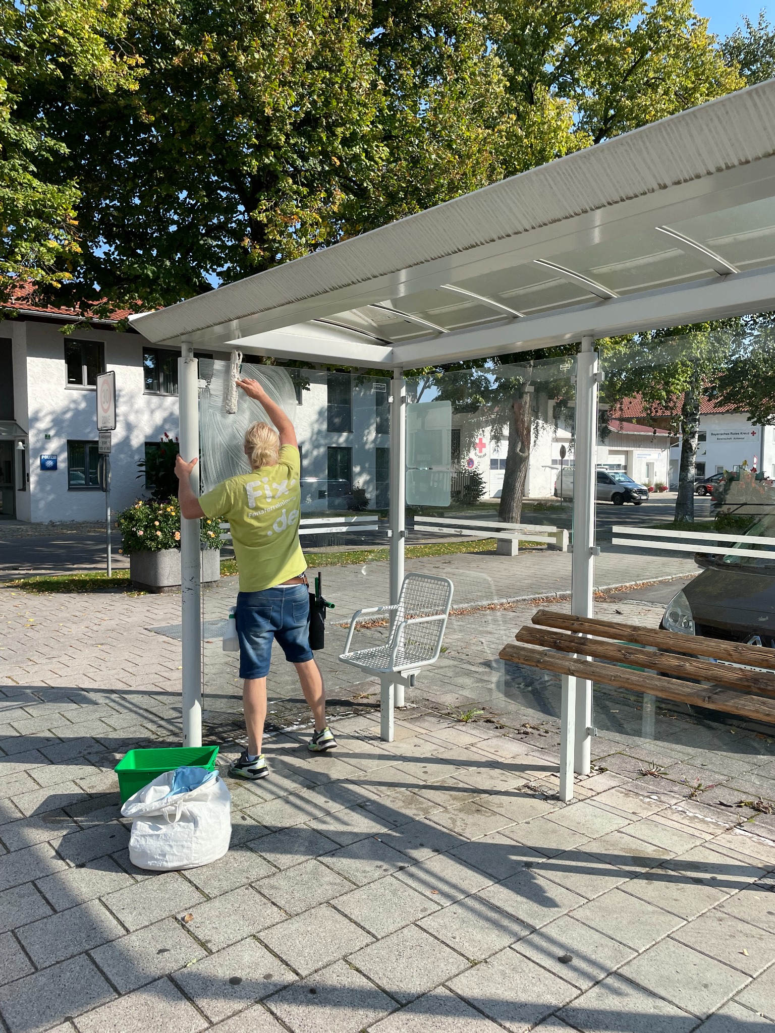 FIX-Mitarbeiter bei der Reinigung der Glasflächen eines Wartehäuschens in Grassau